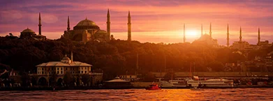 mosques near buildings and body of water during golden hours